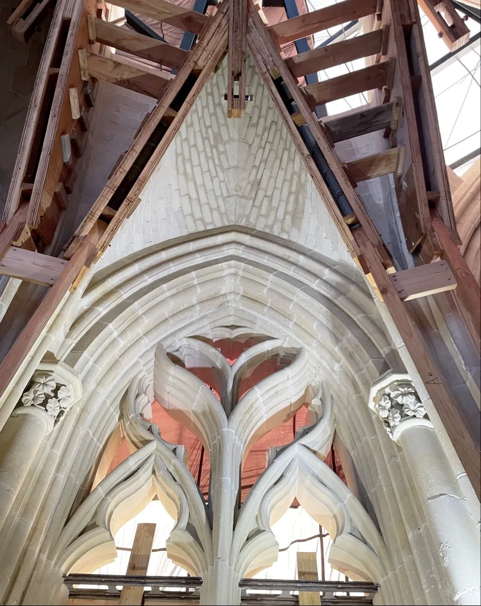 View looking straight up into a finished Gothic stone vaulted ceiling with wooden scaffolding